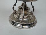 a silver plate with a bird on it on a stand