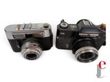 two cameras sitting next to each other on a white surface