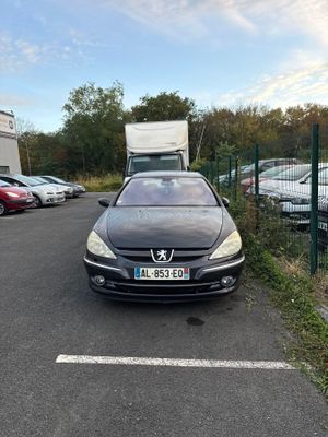 a black car parked in a parking lot next to a fence