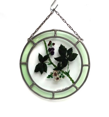 une plaque de verre sur laquelle est représentée une fleur, suspendue à une chaîne