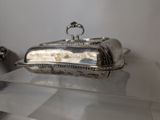 a silver plate with a lid on a glass shelf