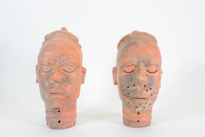 paire de vases en terre cuite rouge représentant des têtes aux yeux fermés sur fond blanc