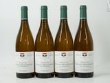 quatre bouteilles de vin sont alignées sur une surface blanche