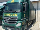 two green trucks parked next to each other in front of a building