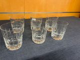 four glasses are lined up on a table in front of a wall