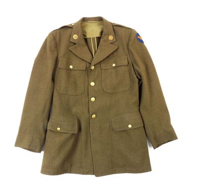 une vieille veste militaire avec un écusson bleu sur la poitrine