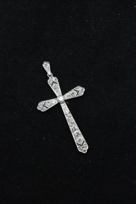 a diamond cross pendant on a black velvet surface