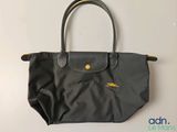 a black longchamp bag sitting on top of a white table