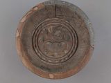 une assiette marron ornée d'un motif sur un fond gris