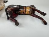 two figurines of a horse laying on the ground