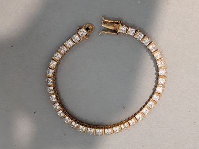 une photo d'un bracelet en diamants posé sur une table, avec l'ombre d'une personne