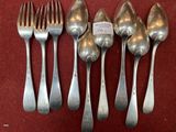 six silver spoons and a fork on a red cloth
