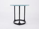 a round glass table with black legs and a black base
