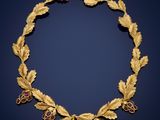 a gold and ruby necklace with leaves and berries