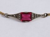 a close up of a necklace with a pink stone on it