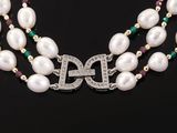 a necklace with pearls and emeralds on a black background