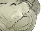 a glass vase with a bird on it on a white surface