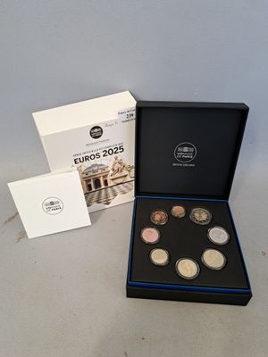 Le coffret de pièces en euros se trouve dans une boîte noire, à côté d'une boîte blanche.