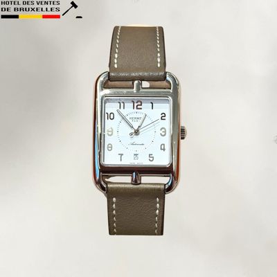 une montre argentée avec un bracelet en cuir marron sur fond blanc