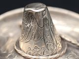 a silver plate with a silver bell on top of it