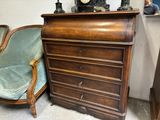 une commode sur laquelle est posée une horloge, à côté d'une chaise