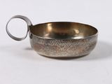 an old silver bowl with a handle on a white surface