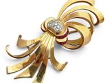 un gros plan d'une broche en or ornée d'un diamant rouge et blanc en son centre