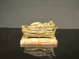 figurine en or représentant une femme endormie sur un banc, posée sur une table noire