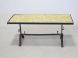 an old table with a yellow tile top and metal legs
