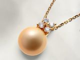 une photo d'un pendentif en or orné d'une perle dorée et de diamants, suspendu à une chaîne en or