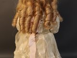 a doll with blonde hair and a white dress on a stand