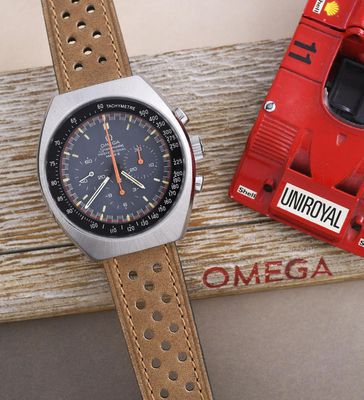 une montre posée sur une table en bois, à côté d'un objet rouge