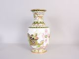 un vase blanc orné d'un motif vert et jaune