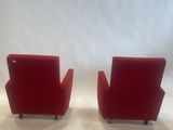 two red chairs sitting on top of a white floor next to a white wall