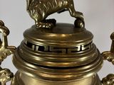 a large brass urn with a lion on top of it