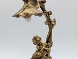 a bronze figurine of a boy and a bird on a branch