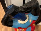 a sculpture of a superman holding a bat on a wooden floor