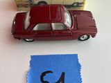 une petite voiture rouge posée sur une table, à côté d'un tissu bleu