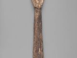 an old wooden spoon with a face on it on a gray surface