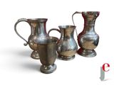 trois vases en argent posés l'un à côté de l'autre sur une surface blanche
