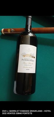 une bouteille de vin et un cigare posés sur une table de billard
