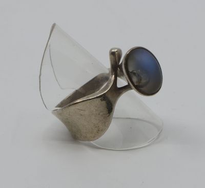 bague en argent ornée d'une pierre bleue au centre, sur une surface transparente