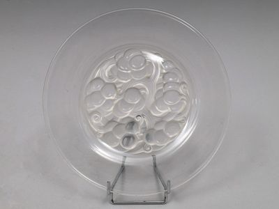 une assiette transparente ornée d'un motif, posée sur un socle