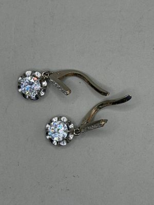 pair of diamond earrings on a hook on a gray surface