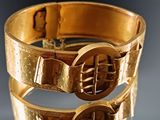 a close up of a gold bracelet with a buckle on it