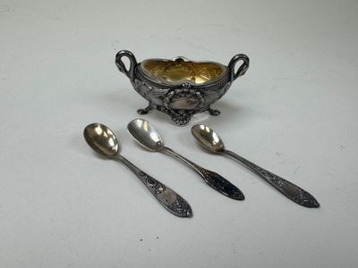 trois cuillères en argent et un bol posés sur une table blanche
