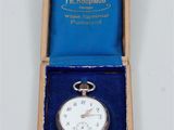 a silver pocket watch in a blue box on a white surface