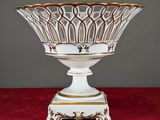a close up of a white and gold bowl on a red surface