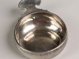 a silver bowl with a spoon in it on a white surface