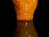 un vase jaune posé sur une surface réfléchissante